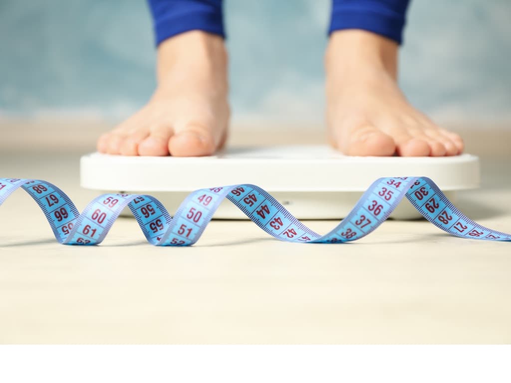 woman standing on scale with a tape measure